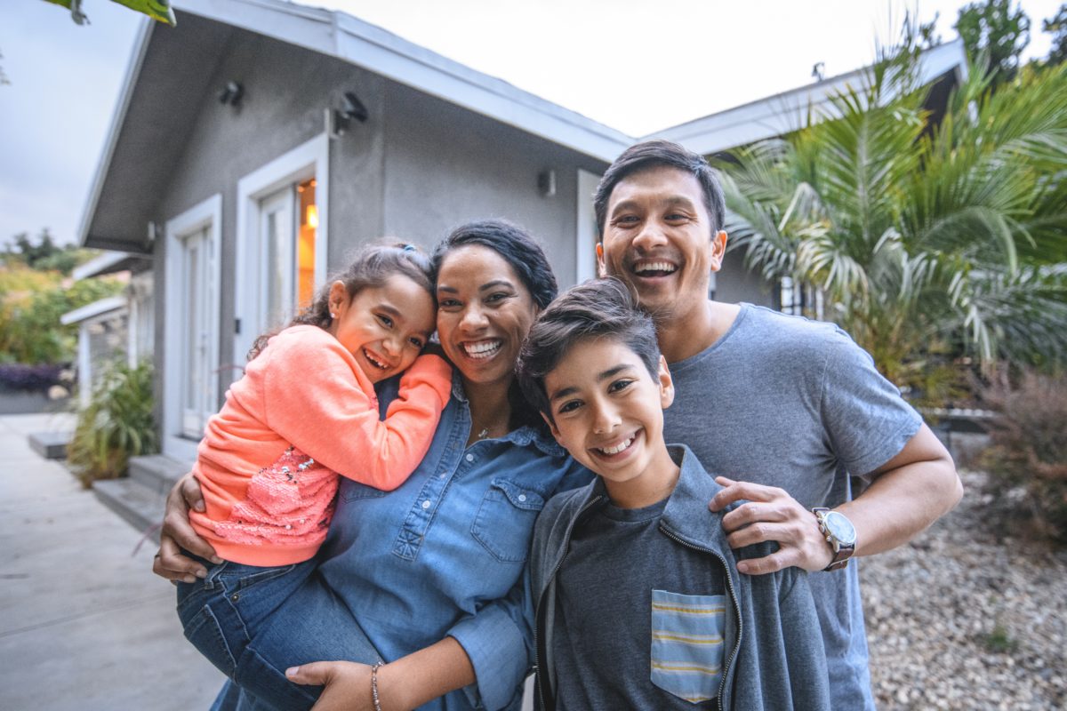 Family Standing in front of their home smiling